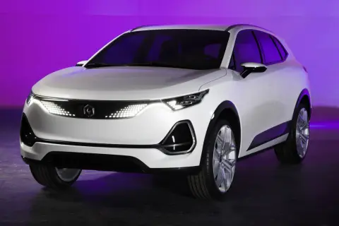 Biały, nowoczesny polski samochód elektryczny z futurystycznymi światłami LED na tle fioletowego światła.