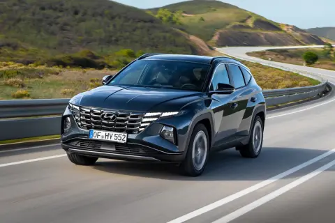 Ciemnoszary Hyundai Tucson na zakręcie drogi. Sprawdź jego imponujące hyundai tucson wymiary i ciesz się jazdą po malowniczej trasie.