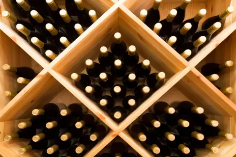 Drewniany stojak na wino wypełniony butelkami.