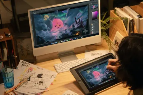 Artysta tworzy fantastyczny świat na tablecie graficznym, używając aplikacji do rysowania. Na ekranie komputera widać jego dzieło w pełnej krasie.