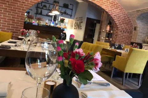 Stolik w jednej z klimatycznych restauracji Lublin. Kwiaty, kieliszki i żółte fotele tworzą przytulną atmosferę.