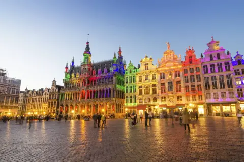 Kolorowe budynki na Grand Place w Brukseli, idealne na święta w Belgii. Ludzie spacerują po brukowanym placu o zmierzchu.