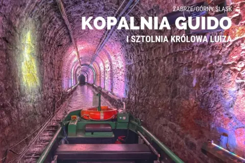 Podziemny spływ w kopalni Guido. Łódź płynie przez oświetlony tunel z kamiennymi ścianami.