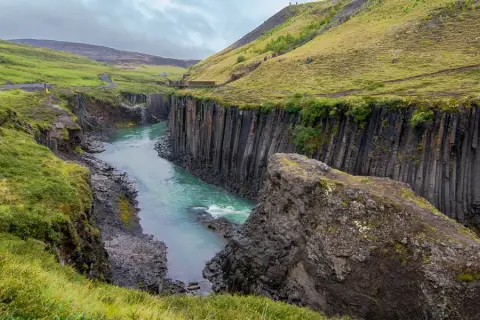Un río turquesa serpentea entre cañones de basalto en Islandia, evocando la majestuosidad de los fiordos islandeses.