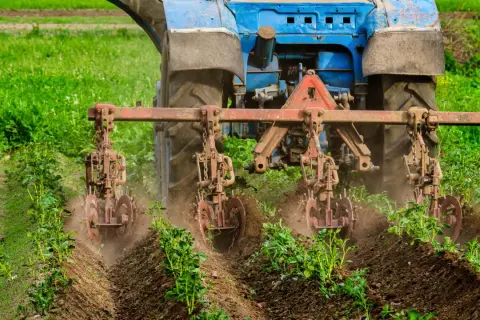 Niebieski traktor z narzędziami uprawia pole, wspierając rolnictwo regeneratywne.