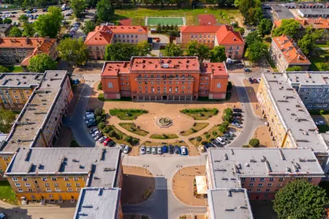 Osiedle Otylia w Tychach z lotu ptaka. Centralny budynek z pomarańczową fasadą, plac z fontanną i otaczające go bloki mieszkalne.