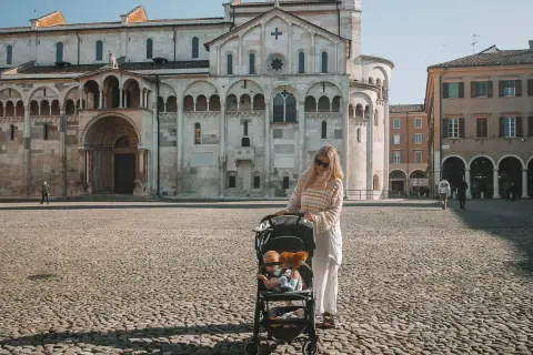 Kobieta z wózkiem dziecięcym na placu przed katedrą w Modenie. To piękne miejsce, które warto zobaczyć, zwłaszcza z taką rodzinną wycieczką.