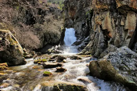 Un río serpentea entre rocas y vegetación hasta una cascada en la ruta de las cascadas del Purgatorio.