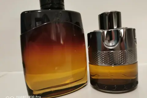 Dwa flakony perfum: jeden z gradientem od czerni do bursztynu, drugi z metalicznym wykończeniem i napisem AZZARO. Idealne na noc.