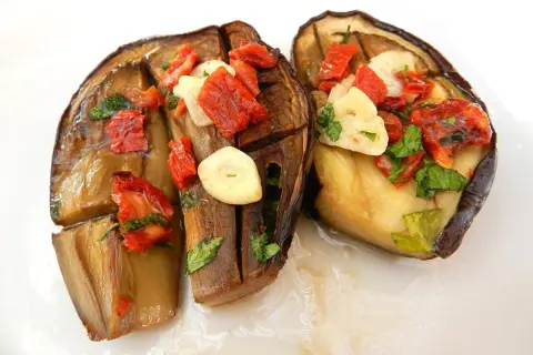 Melanzane alla sassarese, un piatto saporito con melanzane cotte, pomodori secchi, aglio e prezzemolo.
