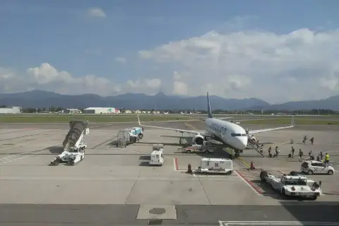 Samolot Ryanair na płycie lotniska Bergamo. W tle góry i budynki lotniskowe.