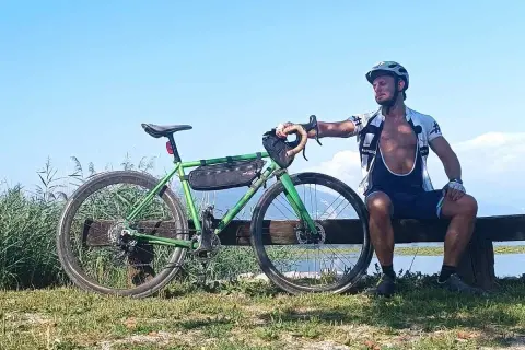Ciclista riposa accanto alla sua bici verde, un promemoria che andare in bici fa dimagrire e dona benessere.