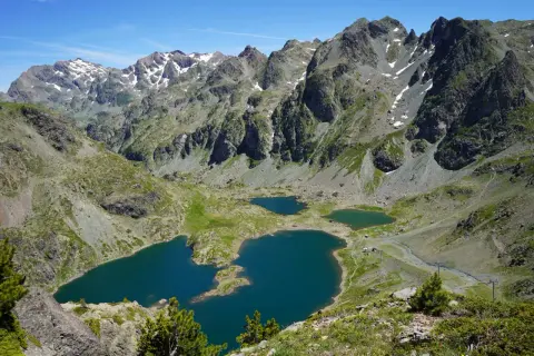 Vue panoramique sur le lac Robert et ses jumeaux, entourés de montagnes escarpées aux sommets enneigés. Un paysage alpin spectaculaire.