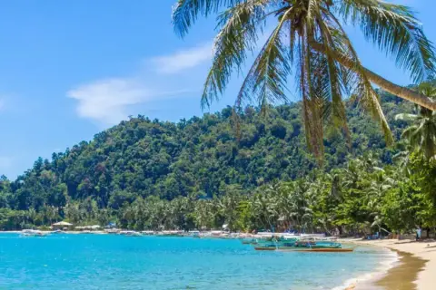 Paradiesische Bucht mit Palmen, türkisfarbenem Wasser und Booten – ideale **Backpacker Reiseziele** für Abenteuerlustige.