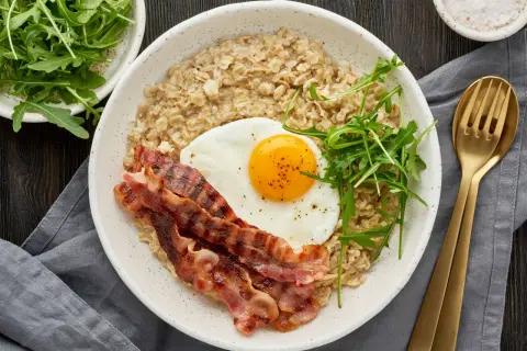 Herzhaftes Frühstück: Haferflocken mit Spiegelei, Speck und Rucola. Wer sagt, dass man Haferflocken abends essen muss? Dieses Gericht ist perfekt für einen energiegeladenen Start in den Tag.