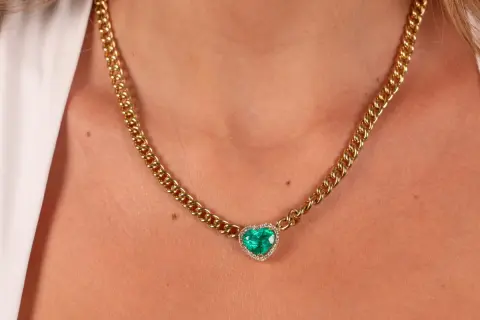 Collar de oro con colgante de corazón de esmeralda y diamantes. Un ejemplo de nombres de joyas que evocan elegancia y amor.