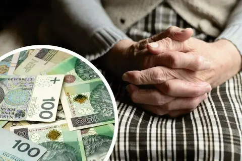 Dłonie starszej osoby splecione na kolanach, obok stos banknotów 100 zł. Symbol wsparcia finansowego, jak 500 plus dla niepełnosprawnych.