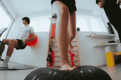 Allenamento per la riabilitazione crociato anteriore: un giovane si allena su una pedana instabile, mentre un altro esegue esercizi di potenziamento.