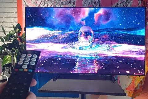 Telewizor wyświetla astronautę w kosmosie, trzymany jest pilot.