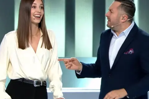 Kobieta i mężczyzna rozmawiają na scenie, mężczyzna wskazuje palcem.