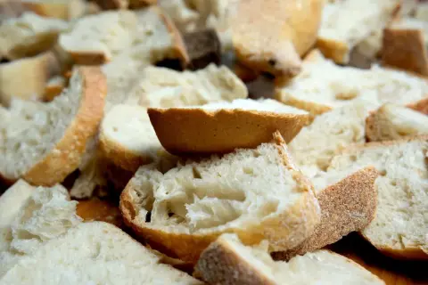 Kawałki czerstwego chleba pokrojone w kostkę i plastry, gotowe do zapiekanki.