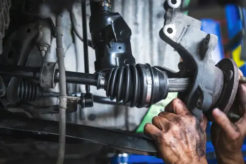 Mécanicien travaillant sur un cardan. Le changement cardan prix est une réparation courante.