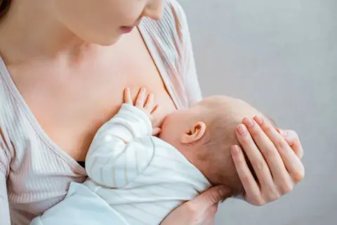 Matka karmi piersią dziecko. To naturalny proces, który wspiera art. 187 Kodeksu pracy, chroniąc prawo do przerw na karmienie.