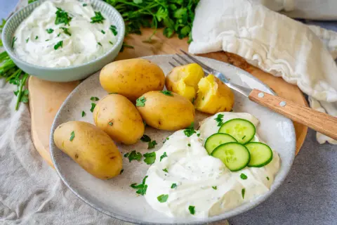 Kleine, gekochte Kartoffeln mit Kräuterquark und Gurkenscheiben – ein einfaches Gericht, das zeigt, wie vielseitig Rezepte mit Kartoffeln als Hauptspeise sein können.