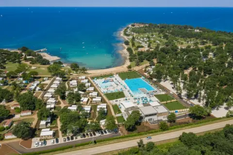 Idealne miejsce, gdzie na wakacje z dziećmi w Europie: kompleks basenów, plaża i domki kempingowe nad turkusowym morzem.