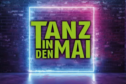 Tanz in den Mai Solingen: Grüne Schrift auf Neon-Rahmen vor Ziegelwand.