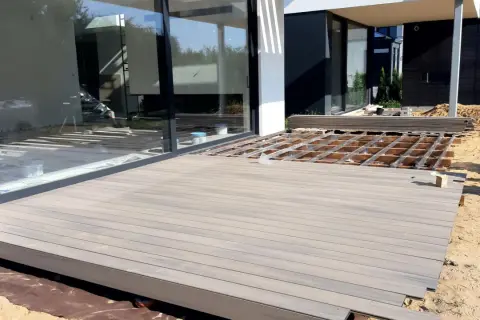 Budowa tarasu z betonu w nowoczesnym domu. Deski kompozytowe czekają na montaż na drewnianym stelażu.