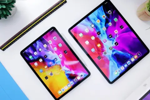 Dwa iPady z kolorową tapetą, obok linijka i niebieska okładka. Dowiedz się, jak przyspieszyć tablet.