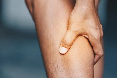 Hand greift an schmerzendes Bein. Was hilft gegen Muskelschmerzen?