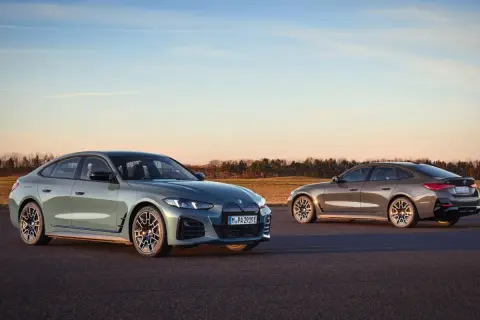 Dwa eleganckie BMW Gran Coupe, jedno zielone, drugie brązowe, stoją na asfalcie o zachodzie słońca.