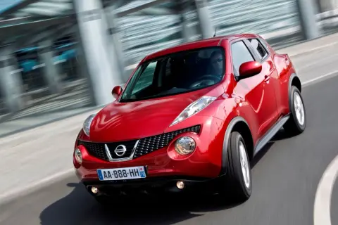 Czerwony Nissan Juke pędzi po drodze, jego dynamiczna sylwetka podkreślona przez ruch.