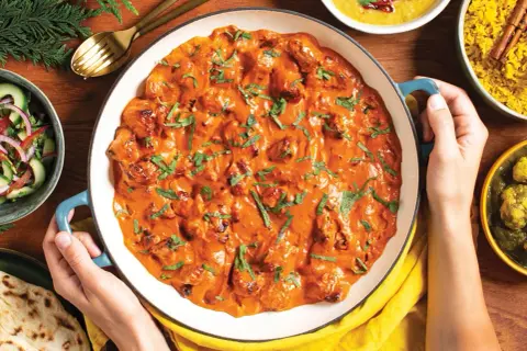Pyszny butter chicken przepis w kremowym sosie, podany z ryżem, sałatką i chlebkiem naan.