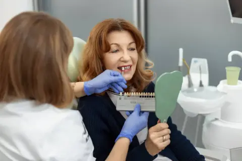 Dentystka pokazuje pacjentce wzornik kolorów, by dobrać idealny odcień licówek. Proces tworzenia pięknego uśmiechu.