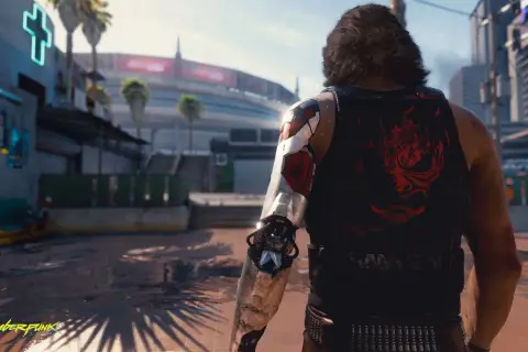 Cyberpunk czas gry: mężczyzna z cybernetycznym ramieniem i koszulką z logo Samurajów stoi na tle futurystycznego miasta.
