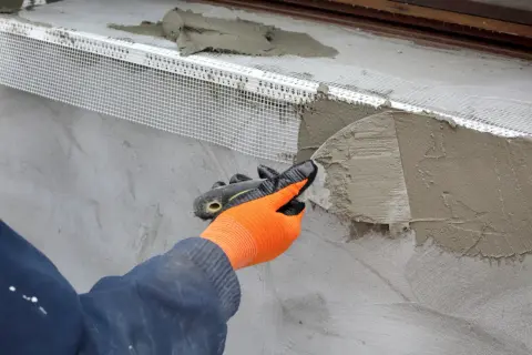 Application d'un enduit isolant extérieur avec une truelle, renforçant la façade.