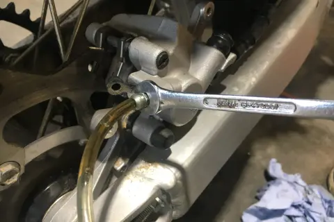 Klucz nasadowy odkręca odpowietrznik podczas wymiany płynu hamulcowego w motocyklu.