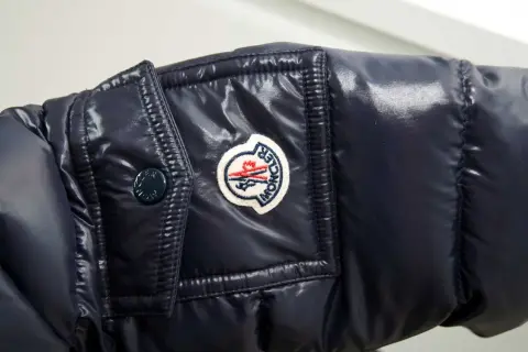 Granatowa, błyszcząca kurtka z naszywką Moncler. Czy to właśnie ta firma, o którą pytasz?