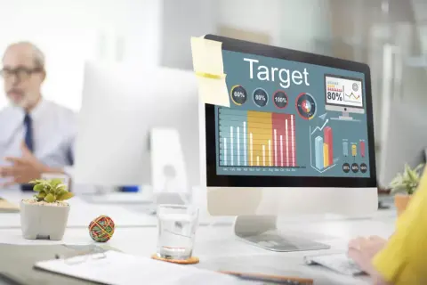 Kobieta analizuje wykresy na ekranie komputera, planując kampanię reklamową w internecie.