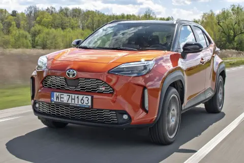 Pomarańczowy Toyota Yaris GR Sport na drodze. Wiele pozytywnych toyota yaris opinie potwierdza jego sportowy charakter i atrakcyjny wygląd.