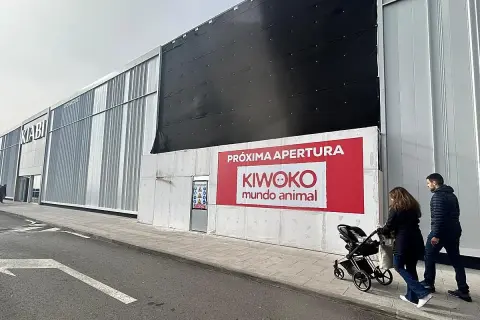 Fachada de tienda Kiwoko con anuncio de próxima apertura y gente paseando.