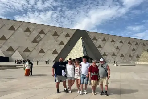 Rodzina pozuje przed nowoczesnym, geometrycznym budynkiem – nowym muzeum w Egipcie.