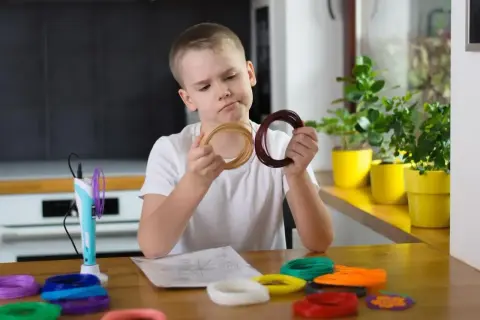 Chłopiec zastanawia się nad kolorami filamentów do drukarki 3D, wspierając swój rozwój sensoryczny.