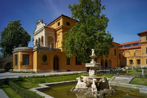 Der kunstbau lenbachhaus mit seinem gelben Anbau und dem Brunnen im Garten.