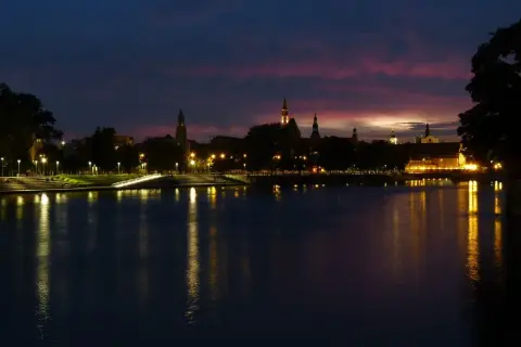 Zachód słońca nad Odrą we Wrocławiu. Idealne miejsce, by zastanowić się, co robić we Wrocławiu wieczorem, podziwiając iluminacje miasta.