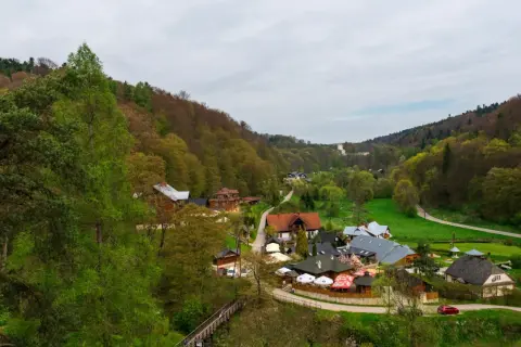 Malownicza dolina w okolicach Krakowa, z zabudowaniami i lasami.