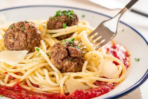 Spaghetti mit drei herzhaften polpetta deutsch, garniert mit Parmesan und Petersilie, serviert mit Tomatensauce.